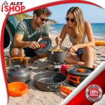 Set aluminijumskog posuđa za kampovanje na plaži dok momak i devojka pripremaju obrok pored mora.