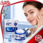 Žena nanosi Blue Copper Peptide kremu sa esencijom lososa na lice, dok se pored nje nalazi otvorena teglica i kutija proizvoda za svakodnevnu anti-age negu kože.